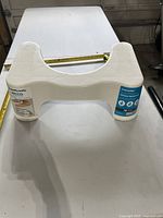 White plastic Squatty Potty Ecco toilet footstool on tabletop with measuring tape