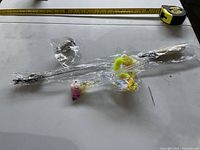 All cat toys laid out in packaging: teaser wand, mouse, assorted balls, spring coil with tape measure for scale