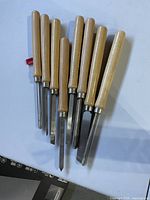 Eight woodturning lathe chisels with wooden handles displayed on table