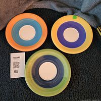 Three hand painted plates showing colour variations and lot tag 55