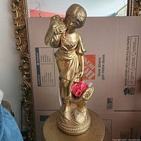Front view of gold painted ceramic statue with bird and flower basket
