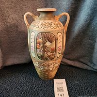 Front view of hand-painted ceramic vase with handles and landscape panel