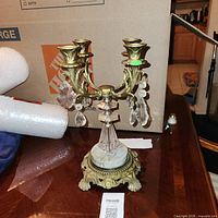 Full view of brass and crystal four-arm candelabra on marble base
