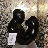 Front view of glossy black embracing couple statue
