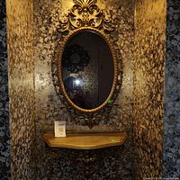 Full view of gold mirror and matching shelf mounted on wall