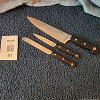 Three Farberware Pro knives laid out on carpet with lot tag