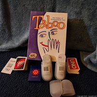 Full lot view showing Taboo box, Uno Attack deck, standard Uno deck, two Umbra Ante card decks