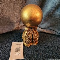 Front view of gold sphere on pedestal