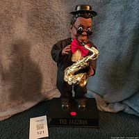 Front view of Jazzman doll on base showing saxophone and button