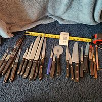 Full layout of knives and utensils on carpet with tape measure