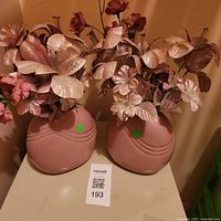 both mauve plastic vases with faux floral arrangements