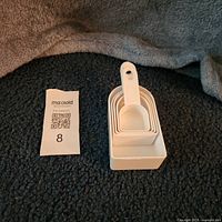 Five white plastic measuring scoops stacked