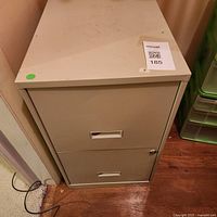 Full view of beige metal two-drawer cabinet with lock and recessed pulls