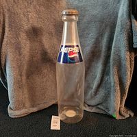 Full view of large clear plastic Pepsi bottle coin bank standing upright