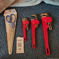 Three red pipe wrenches and packaged shears overview