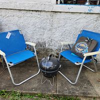 Overall view showing two blue folding beach chairs and black kettle grill