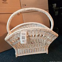 Full view of white wicker magazine basket with handle