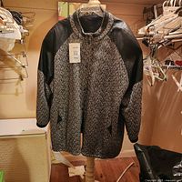 Front view of herringbone coat with faux leather sleeves on dress form