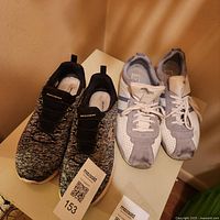 Both pairs of sneakers side by side on table