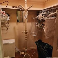 Full view of cream wooden coat rack in closet setting
