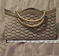 Front view of beige/gold brocade purse with tape for width measurement