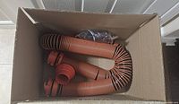 Hose inside box showing orange swivel fittings and corrugated hose