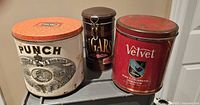 Front view of all three tins showing branding and lids