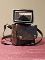 Aqua North Point compass resting atop its leather case, strap visible