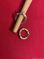 Hoop earrings on red cloth with dowel showing twist pattern and closure style