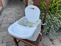 Front view of booster seat attached to wooden chair showing tray and backrest
