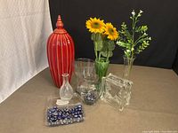 Group shot of all items including red ceramic jar, glass vases, glass block, faux flowers, bead tray
