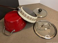 Overview showing red pot, patterned frying pan, both lids