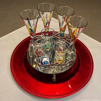 Full set on red charger showing liqueur glasses, shot glasses and tray