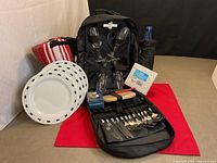 Full set displayed showing backpack open with plates, glasses, cutlery, blanket, bottle and accessories
