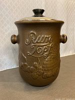 Front view of brown stoneware Rumtopf pot with replacement lid in place