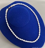 Full view of pearl necklace on display form