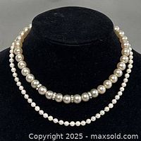 Both pearl necklaces displayed on black bust