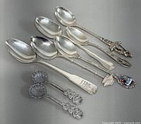 All eight silver souvenir spoons arranged for overview
