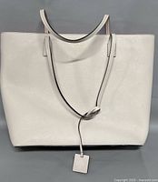 Front view of light beige Kate Spade tote bag with hanging tag visible