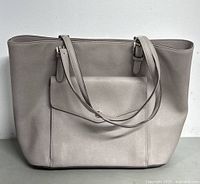 Front view of light gray saffiano leather Michael Kors tote with dual straps and front pocket.