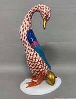 Front left view of Herend goose figurine showing rust fishnet pattern and golden egg