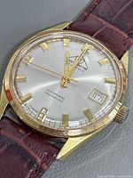 Front view of Mondaine watch showing dial, markers, date window and gold-tone case