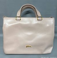 Front view of light beige Longchamp leather handbag showing gold hardware and logo