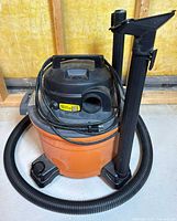 Overall view of Ridgid orange canister vacuum with hose, wands and nozzle