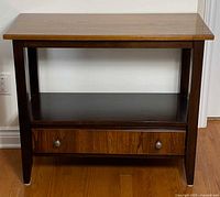 Front view of console table showing top, shelf, drawer, tapered legs