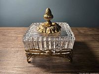 Front view showing cut glass panels, brass acorn finial lid and ornate brass base