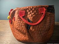 Left side view showing feather texture, red handle, zipper