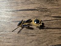 Front view of gold-tone floral brooch on wood surface