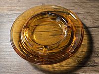 Top view of round amber glass ashtray showing four rests