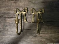 Front view of both brass bow sconces showing design and candle cups